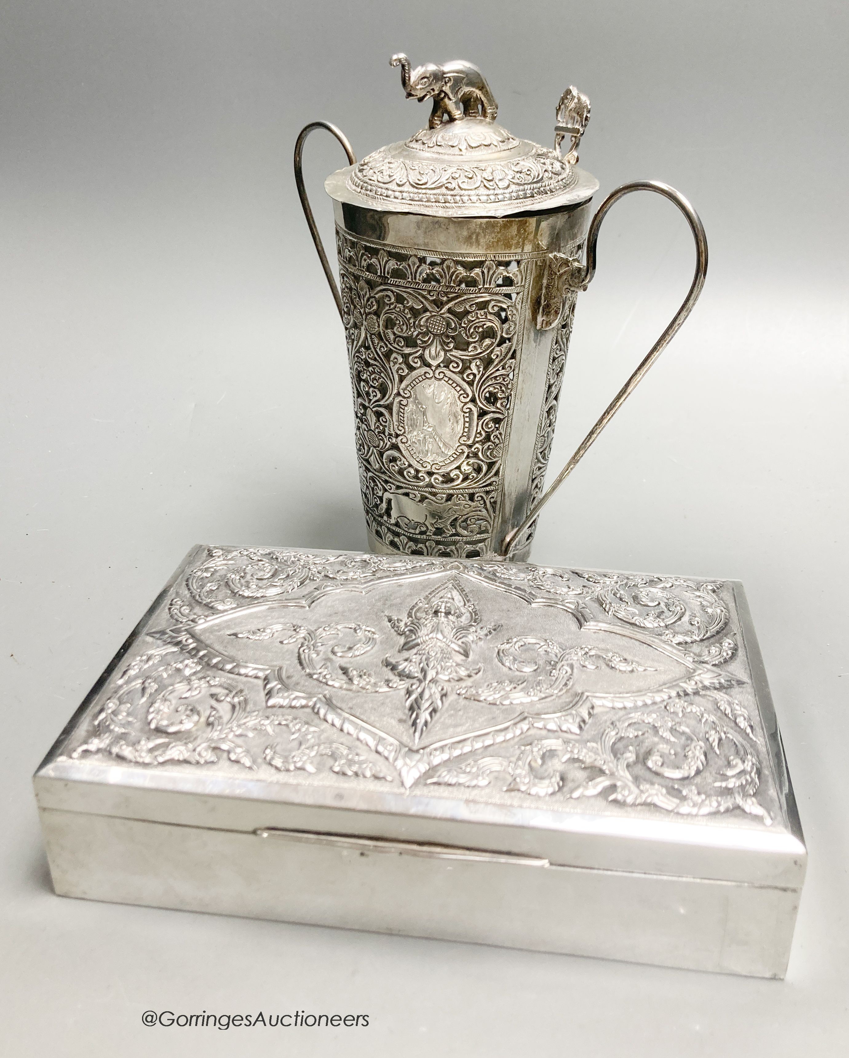 A Thai white metal rectangular cigarette box with embossed lid, 17cm and a Thai white metal cocktail mixer, cover and spoon, engraved
